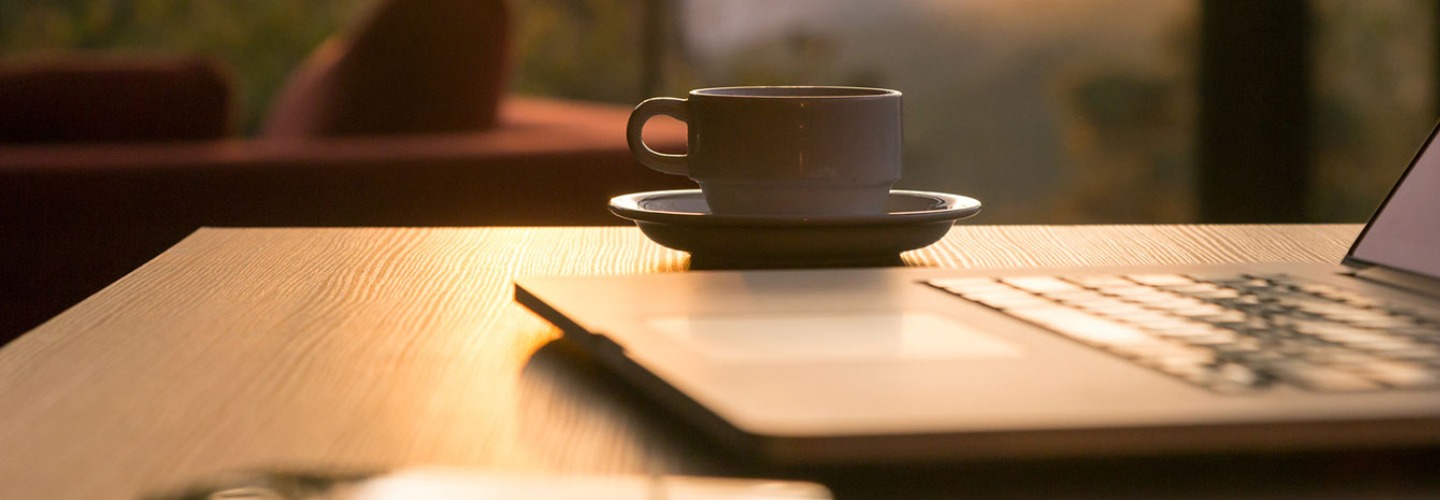 cup of coffee next to a laptop computer